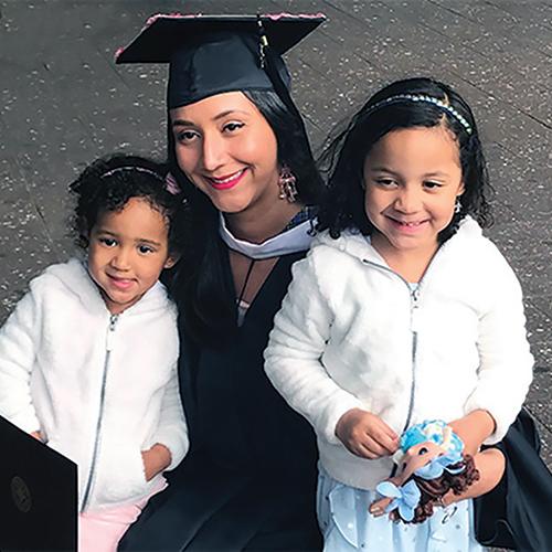 Jaridy Fabre in her commencement regalia with her two small daughters.