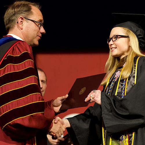 Past president Nyre hands a diploma to a graduate.