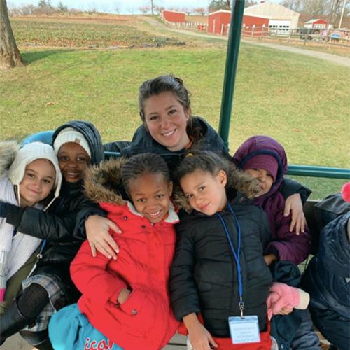 Gina Tomaj with her students on a bench outside at a farm.