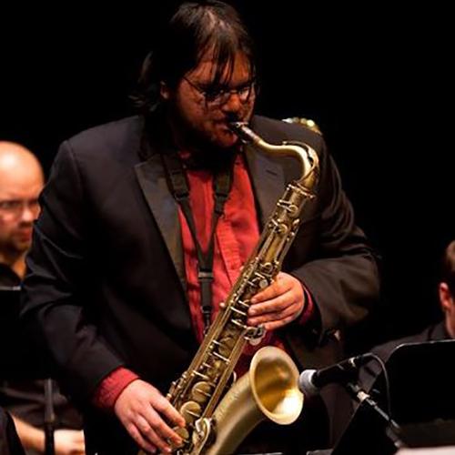 Adam Rosado playing saxophone in a big band.