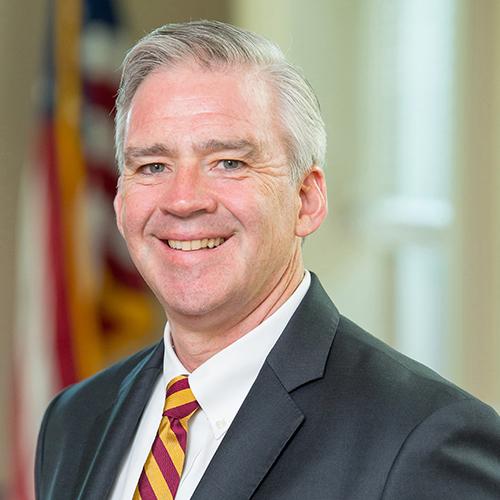 Seamus Carey, Ph.D., president of Iona College with the American Flag in the background.
