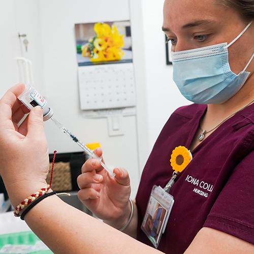 An Iona nursing student prepares a COVID-19 vaccine shot.