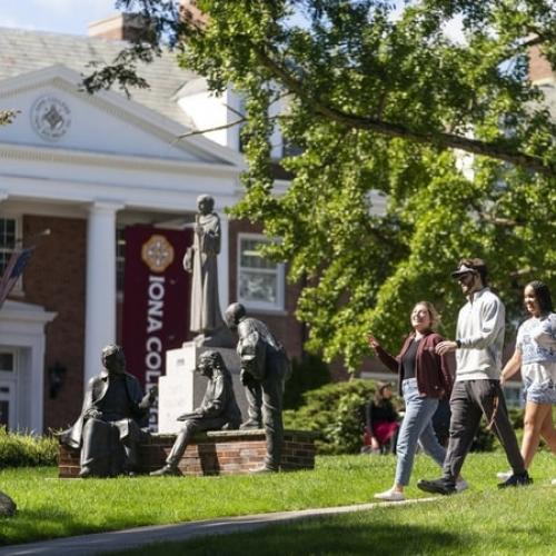 Students Walking on Campus on Path in front of Statues