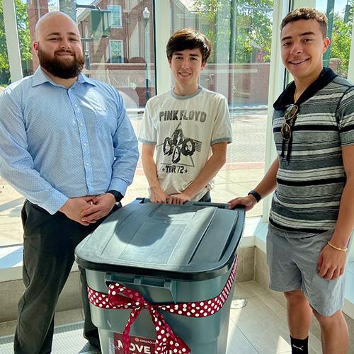 An RA and two high school students collect clothing for the Sharing Shelf.