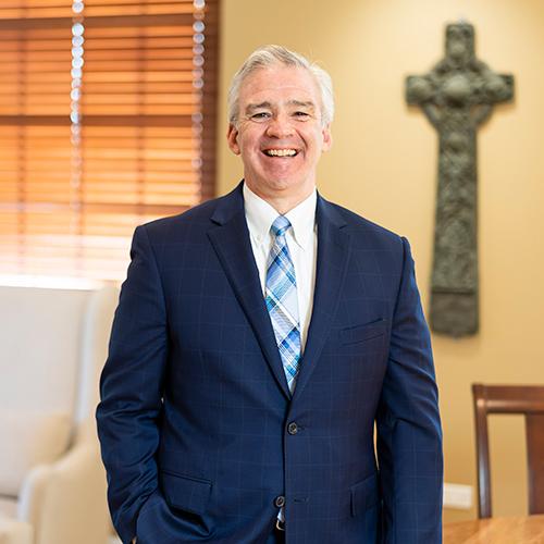 President Carey in his office with the Celtic Cross in the background.