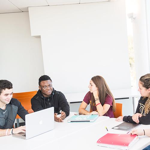 MFT students sit at a table and discuss a project.