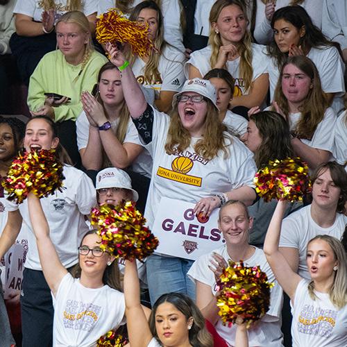 Students stand and cheer at an Iona basketball game.