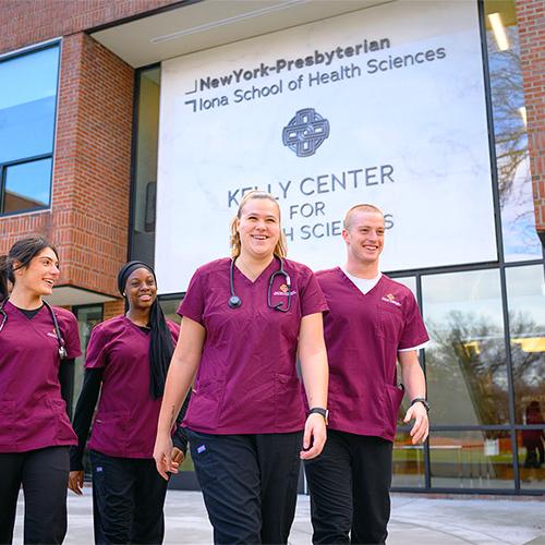 Four students walking by the Kelly Center for Health Sciences.