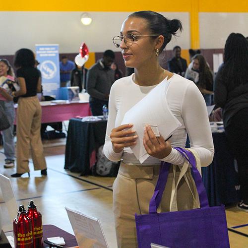 A student holds her resume and talks to a recruiter at the Career Fair.