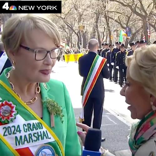 Maggie Timoney with the Grand Marshal sash and NBC New York logo being interviewed at the parade.