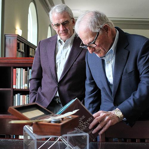 President Carey and Sid Lapidus look at a Thomas Paine book.
