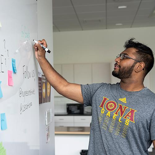 A student works at the white board in the Hynes Institute.