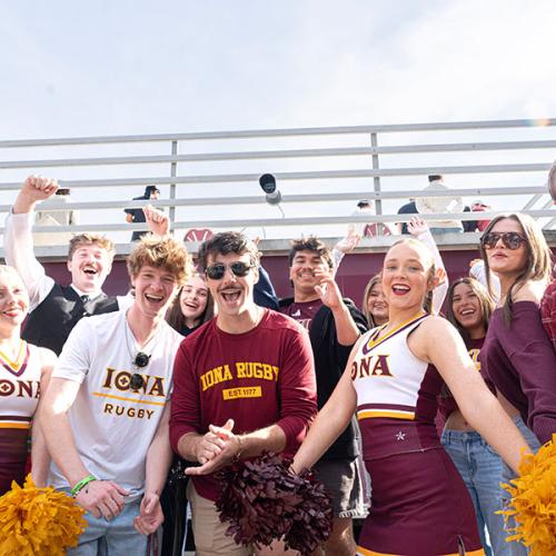 A group of enthusiastic Iona University students and cheerleaders posing together during an outdoor event.