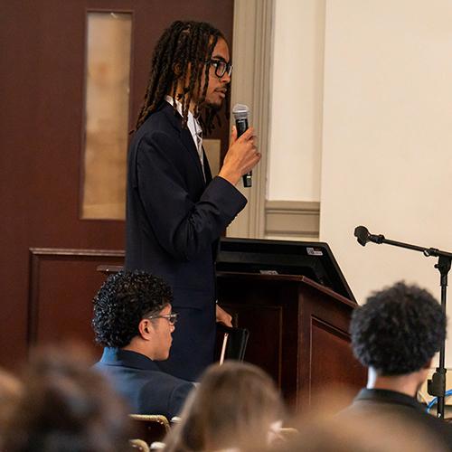 A student standing and speaking into the microphone.