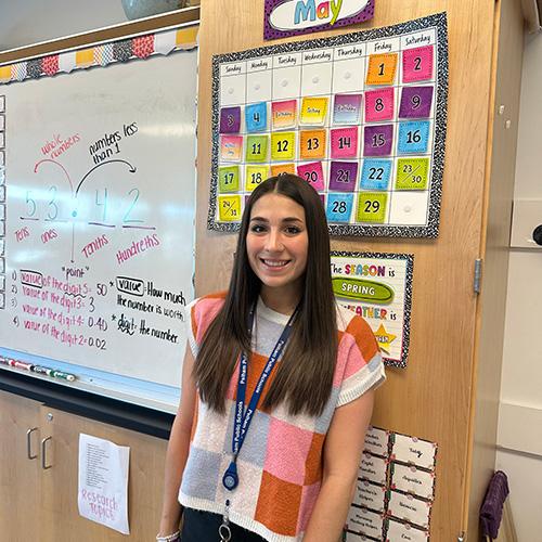 Victoria Schepis smiling and standing in a classroom.