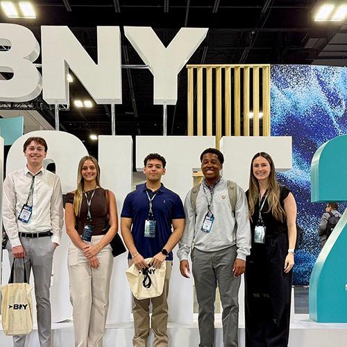 Five attendees pose together in front of a large BNY Insite 26 display sign at the Gaylord Rockies Resort in Aurora, Colorado.