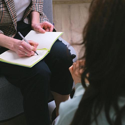 A mental health counselor takes notes during a session.