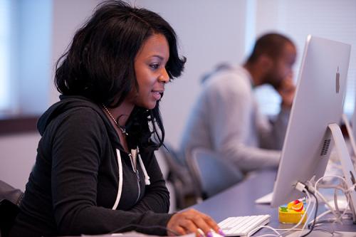 A student works on her online MBA at a desktop computer.