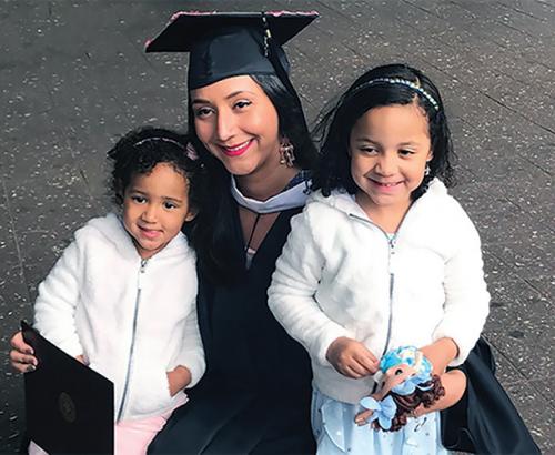 Jaridy Fabre in her commencement regalia with her two small daughters.