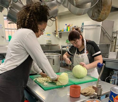 Two students from Mission and Ministry volunteer in a kitchen.