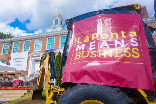 A backhoe with a tarp that reads LaPenta Means Business at the groundbreaking ceremony.