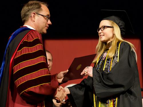 Past president Nyre hands a diploma to a graduate.