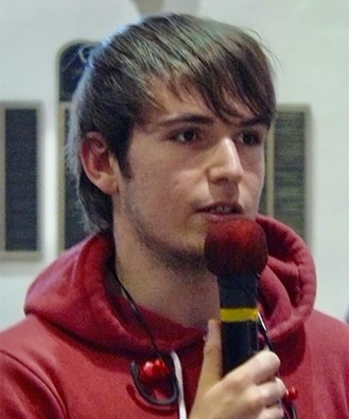 A student holding a microphone and asking a question at a presentation.