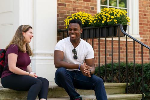 Two Iona students sit on the steps of the advising center and talk.