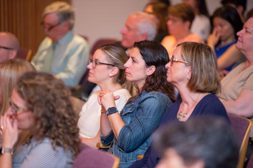 Members of the faculty listen intently at a college meeting.