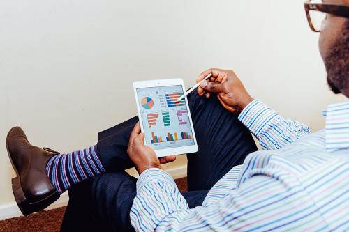 A man looks at several charts and graphs on a digital tablet.