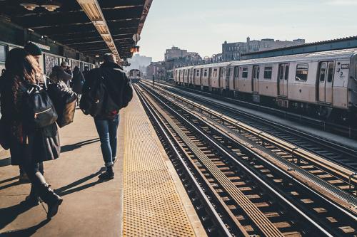 Commuters stand on a train platform waiting for the train.