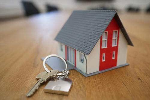 A small house and a key placed next to it are sitting on top of a table.