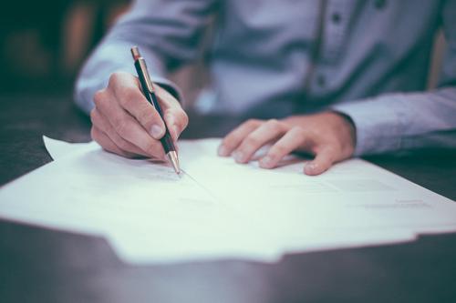 A man is using a pen to write on a document.