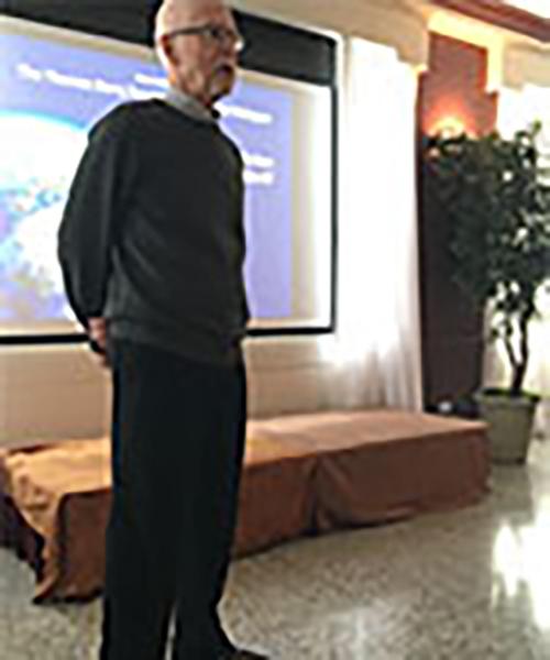 Brother Cawley stands in front of a projector and presents in the Burke Lounge.