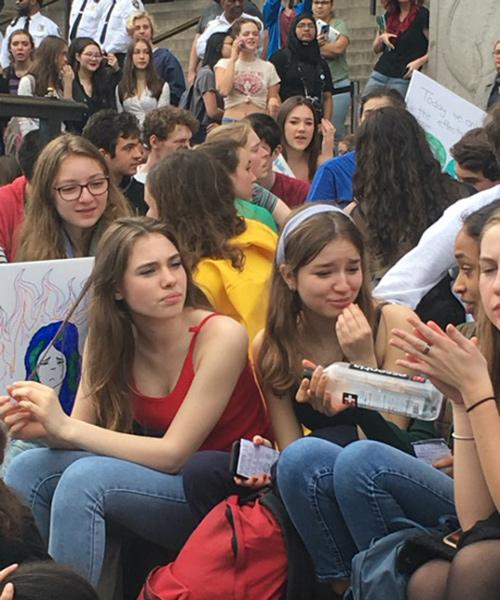 A group of young demonstrators for climate change sit together.