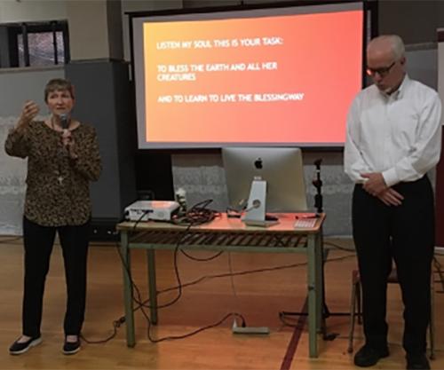 Sr. Deignan speaks as she stands in front of a projector with Br. Cawley.