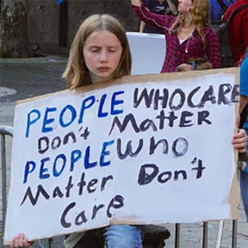 A girl holds a homemade sign in support of climate change.