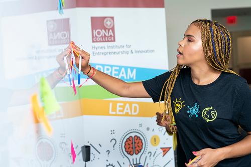 A student writes on a white board in the Hynes Center for Entrepreneurship.