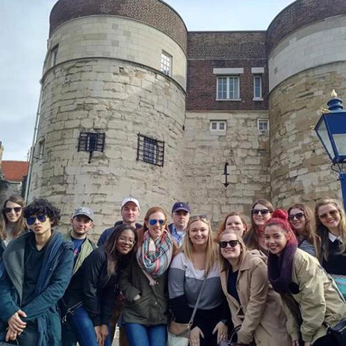 Iona students pose in front of a castle like building in London, England.