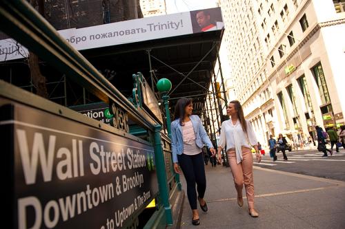 Two students walk on the street in New York City near the Wall Street subway.