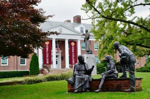 The "To Teach" statue in the Iona campus quad with McSpedon Hall in the background