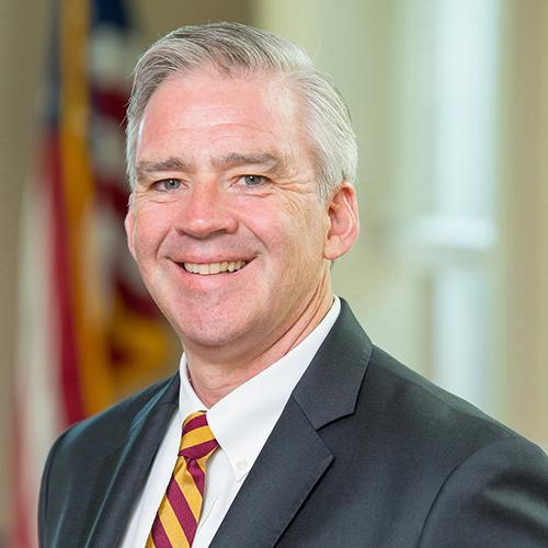 Seamus Carey, Ph.D., president of Iona University with the American Flag in the background.