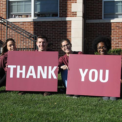 Four students hold a sign saying thank you for Giving Gaels Day.