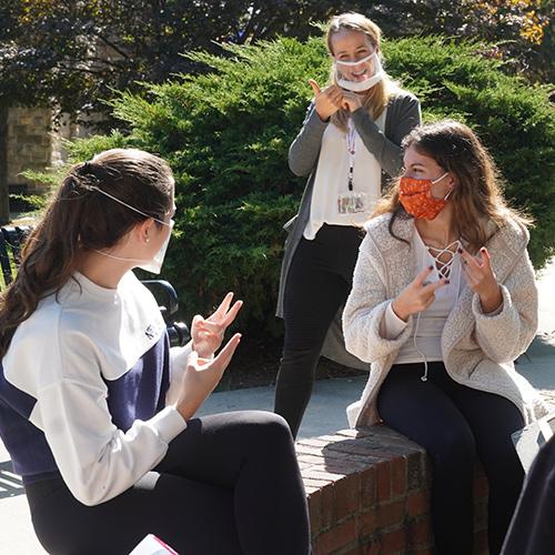 Dr. Michelle Veyvoda signing with students at Iona University. 