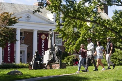 Students Walking on Campus on Path in front of Statues