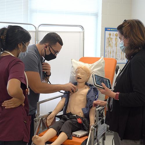 Students practice listening to a patient's heart.