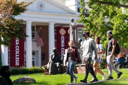 Students walk in front of McSpedon hall on a sunny day.