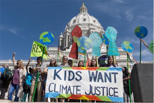 A march in D.C. with children holding a "Kids want Climate Justice" sign. 