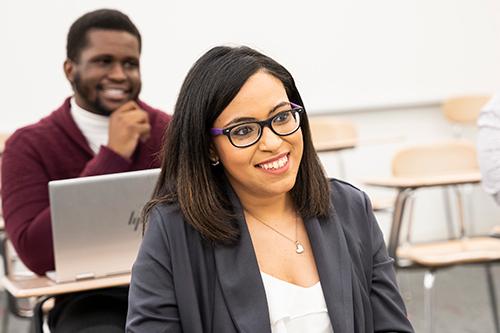 A student in a business class smiles at her desk.