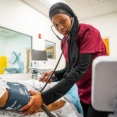 A nursing student practices measuring someone's blood pressure.